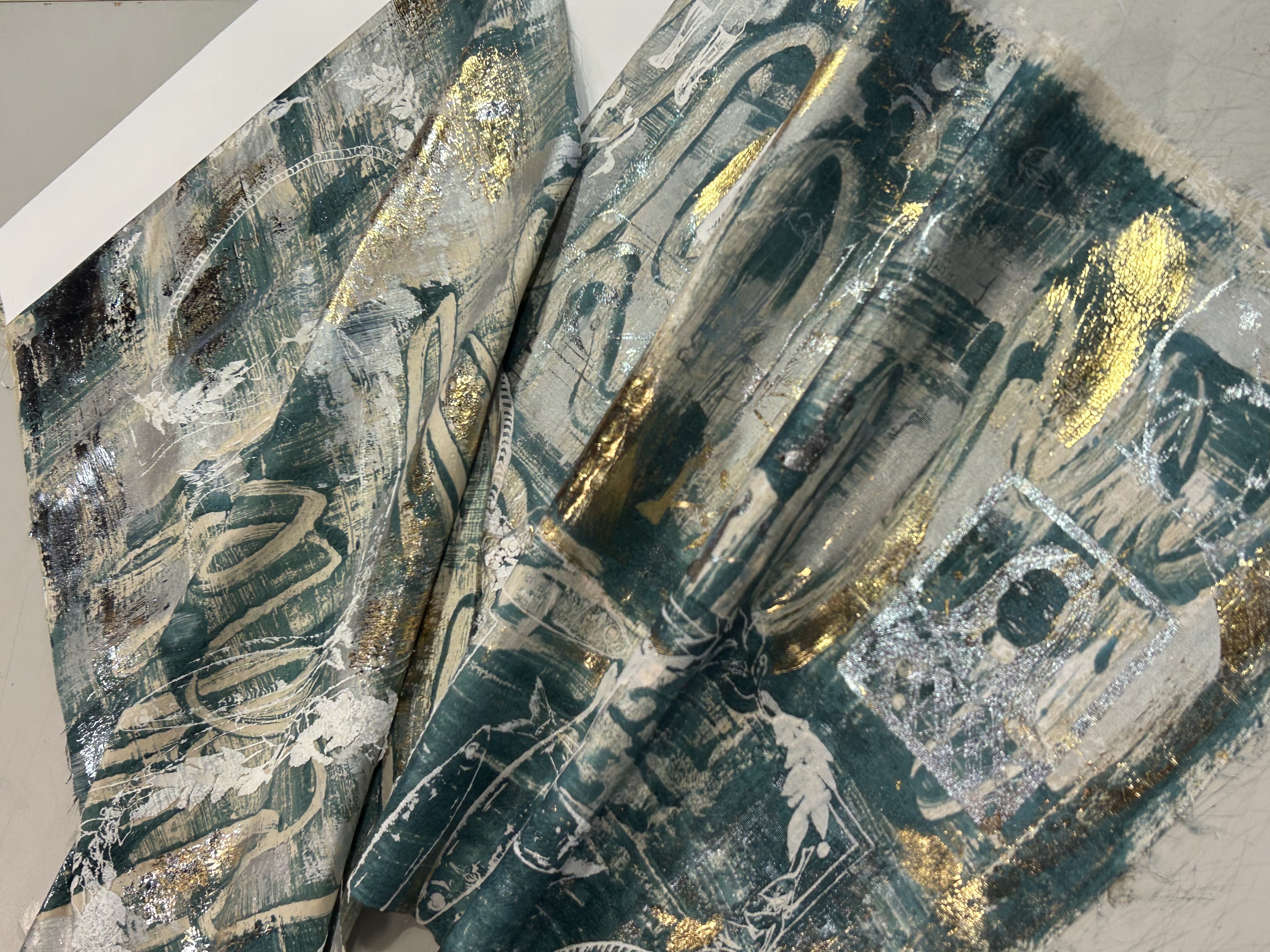 Close detail of a layered teal, silver and gold textile surface